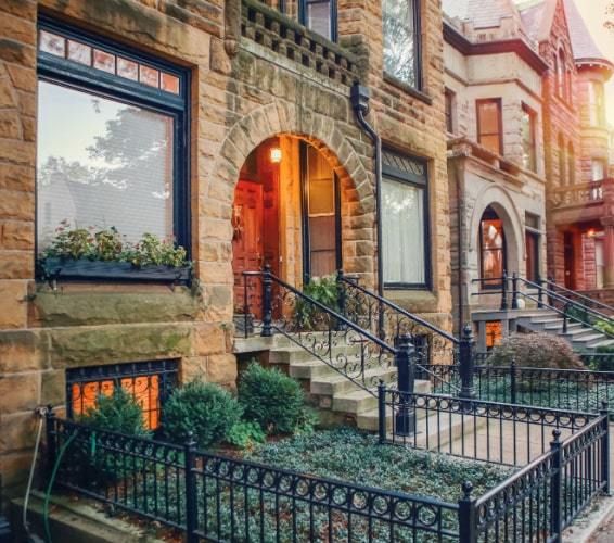 Brick rowhouses lined up in a neighborhood with small fencing